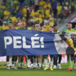 
              Brazilian players hold a banner in honour of the 82-year-old Brazilian soccer legend Pele who is in a hospital in San Paulo recovering from a respiratory infection at the end of the World Cup round of 16 soccer match between Brazil and South Korea at the Stadium 974 in Doha, Qatar, Monday, Dec. 5, 2022. (AP Photo/Jin-Man Lee)
            