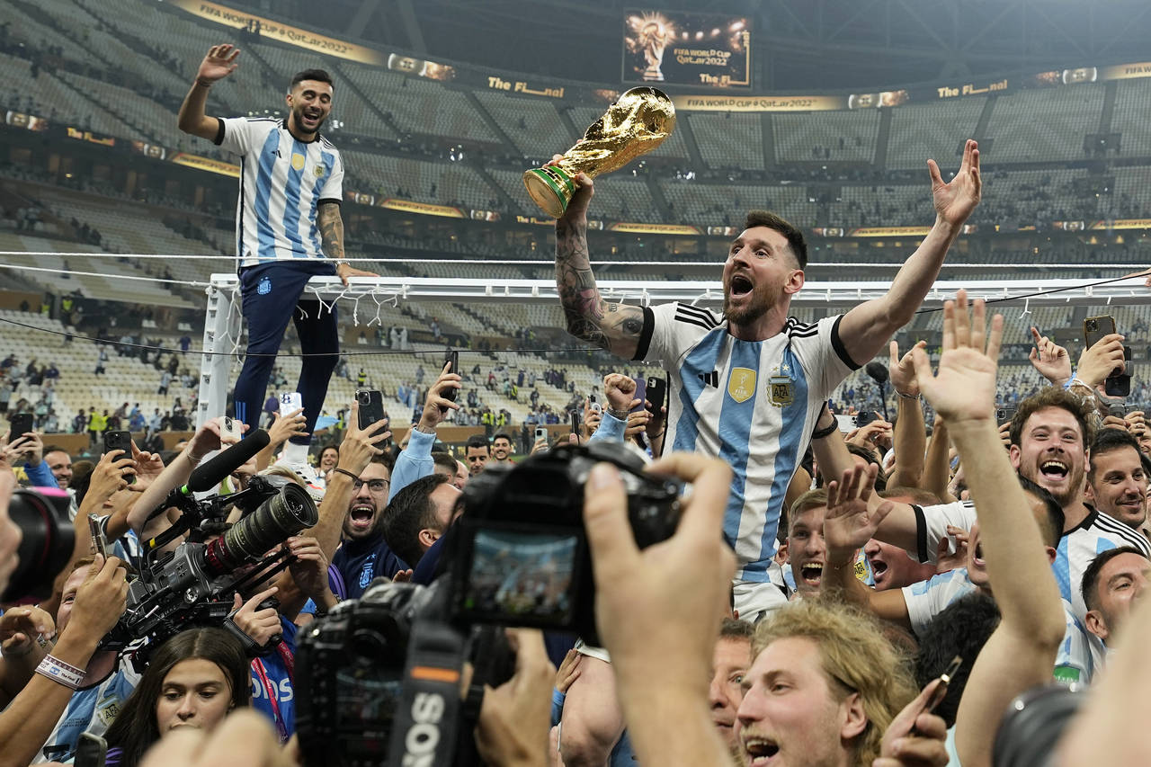 Argentina's Lionel Messi celebrates with the trophy in front of the fans after winning the World Cu...