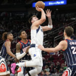 
              Dallas Mavericks guard Luka Doncic, center top, shoots over Houston Rockets center Alperen Sengun (28) during the first half of an NBA basketball game, Friday, Dec. 23, 2022, in Houston. (AP Photo/Eric Christian Smith)
            