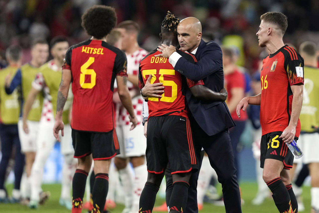 Belgium's head coach Roberto Martinez embraces Belgium's Jeremy Doku after their team was defeated ...