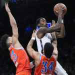 
              Brooklyn Nets' Edmond Sumner, top right, drives past Oklahoma City Thunder's Kenrich Williams (34) and Tre Mann (23) during the first half of an NBA basketball game Sunday, Jan. 15, 2023, in New York. (AP Photo/Frank Franklin II)
            