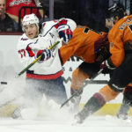 
              Washington Capitals right wing T.J. Oshie (77) passes the puck as he is hit by Arizona Coyotes center Travis Boyd, second from right, as Coyotes defenseman Juuso Valimaki (4) looks on during the first period of an NHL hockey game in Tempe, Ariz., Thursday, Jan. 19, 2023. (AP Photo/Ross D. Franklin)
            