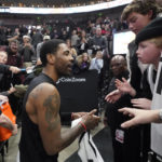 
              Brooklyn Nets guard Kyrie Irving, center, speaks with a fan following their victory over the Utah Jazz after an NBA basketball game Friday, Jan. 20, 2023, in Salt Lake City. (AP Photo/Rick Bowmer)
            