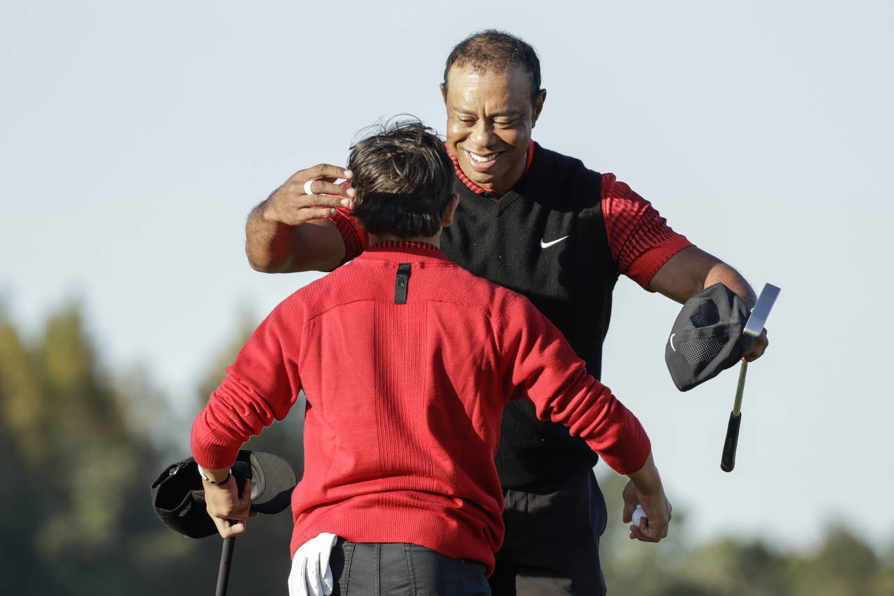 Tiger Woods, right, hugs his son Charlie Woods, left, after finishing the 18th hole during the fina...