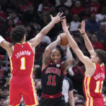 
              Chicago Bulls' DeMar DeRozan (11) looks to pass under pressure from Atlanta Hawks' Jalen Johnson (1) and Bogdan Bogdanovic during the first half of an NBA basketball game Monday, Jan. 23, 2023, in Chicago. (AP Photo/Charles Rex Arbogast)
            
