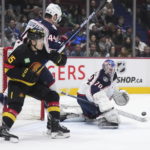 
              Columbus Blue Jackets goalie Joonas Korpisalo (70) makes a save as Erik Gudbranson (44) checks Vancouver Canucks' Sheldon Dries (15) during the first period of an NHL hockey game Friday, Jan. 27, 2023, in Vancouver, British Columbia. (Darryl Dyck/The Canadian Press via AP)
            