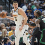 
              Denver Nuggets center Nikola Jokic, left, looks to pass the ball as Boston Celtics guard Jaylen Brown, front right, and center Al Horford defend in the first half of an NBA basketball game, Sunday, Jan. 1, 2023, in Denver. (AP Photo/David Zalubowski)
            