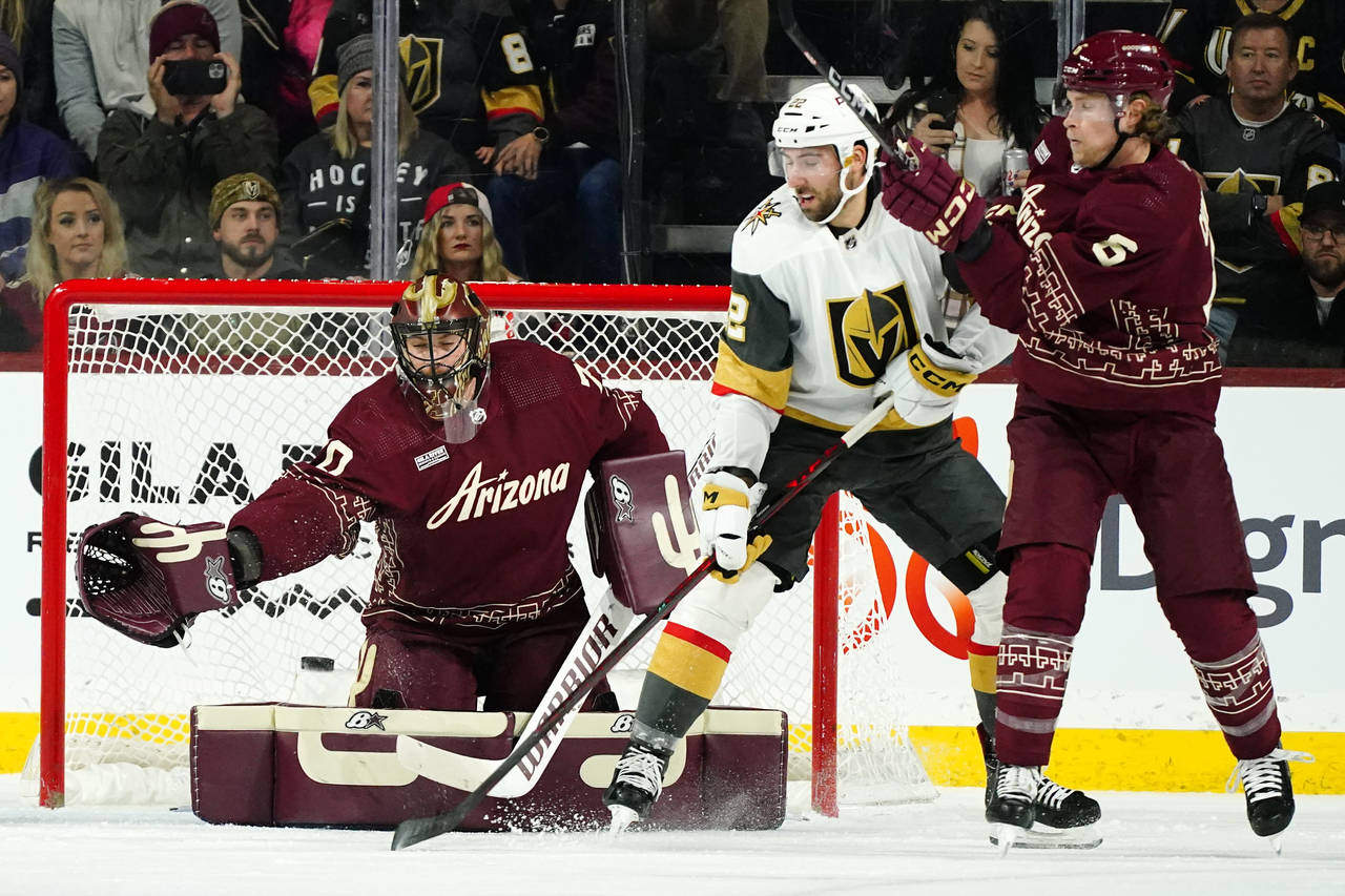 Arizona Coyotes right wing Dylan Guenther (11) and Vegas Golden Knights  right wing Reilly Smith (19) battle for position during the second period  of an NHL hockey game in Tempe, Ariz., Sunday