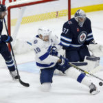 
              Tampa Bay Lightning's Corey Perry (10) tips the puck toward Winnipeg Jets goaltender Connor Hellebuyck (37) as Jets' Dylan DeMelo (2) defends during second-period NHL hockey game action in Winnipeg, Manitoba, Friday, Jan. 6, 2023. (John Woods/The Canadian Press via AP)
            