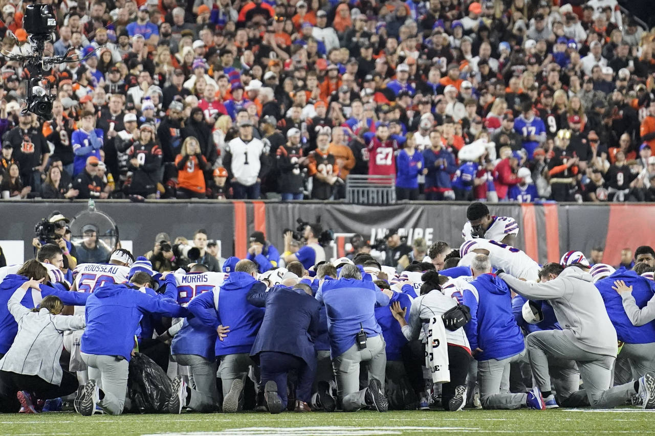 Buffalo Bills players and staff pray for Buffalo Bills' Damar Hamlin during the first half of an NF...