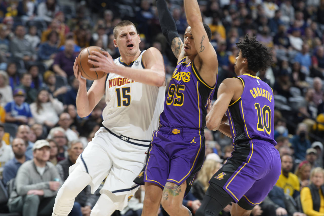 Denver Nuggets center Nikola Jokic, left, drives to the basket as Los Angeles Lakers forward Juan T...