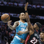 
              Charlotte Hornets forward P.J. Washington, left, passes around Miami Heat forward Jimmy Butler (22) during the first half of an NBA basketball game in Charlotte, N.C., Sunday, Jan. 29, 2023. (AP Photo/Nell Redmond)
            