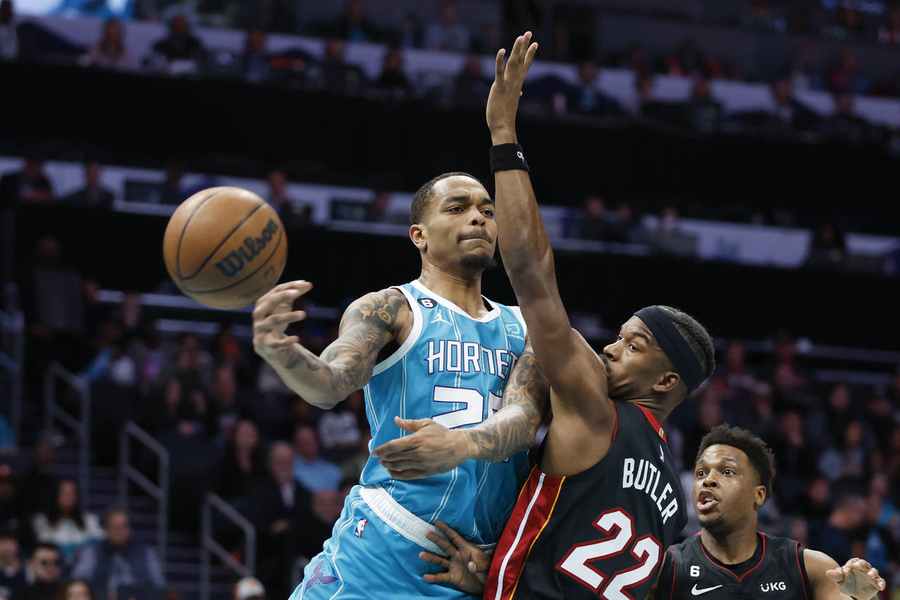 Charlotte Hornets forward P.J. Washington, left, passes around Miami Heat forward Jimmy Butler (22)...