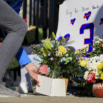 
              A person leaves flowers for the display set-up for Buffalo Bills' Damar Hamlin outside of University of Cincinnati Medical Center, Wednesday, Jan. 4, 2023, in Cincinnati. Hamlin was taken to the hospital after collapsing on the field during the Bill's NFL football game against the Cincinnati Bengals on Monday night. (AP Photo/Aaron Doster)
            