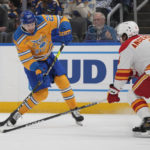 
              St. Louis Blues' Noel Acciari (52) shoots past Calgary Flames' Rasmus Andersson (4) during the second period of an NHL hockey game Tuesday, Jan. 10, 2023, in St. Louis. (AP Photo/Jeff Roberson)
            