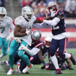 
              Miami Dolphins running back Raheem Mostert (31) pushes away New England Patriots safety Devin McCourty, right, while trying to break free from linebacker Josh Uche, rear, during the first half of an NFL football game, Sunday, Jan. 1, 2023, in Foxborough, Mass. (AP Photo/Steven Senne)
            