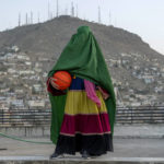
              An Afghan woman poses with a basketball in Kabul, Afghanistan, Thursday, Sept. 8, 2022. The ruling Taliban have banned women from sports as well as barring them from most schooling and many realms of work. A number of women posed for an AP photographer for portraits with the equipment of the sports they loved. Though they do not necessarily wear the burqa in regular life, they chose to hide their identities with their burqas because they fear Taliban reprisals and because some of them continue to practice their sports in secret. (AP Photo/Ebrahim Noroozi)
            