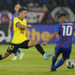 
              FILE - Huang Kaizho of Guangzhou Evergrande, left, fights for the ball against Leandro Velazquez of Johor Darul Ta'zim during their AFC Champions League group I soccer match at Sultan Ibrahim Stadium in Johor, Malaysia, on April 15, 2022. After three years of isolation and financial struggles in Chinese soccer the country is reopening its borders and economy to the outside world. With it, frustrated fans, financially-challenged clubs and unpaid players in the Chinese Super League might receive some long-awaited good news. (AP Photo/Vincent Thian)
            