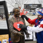 
              Fan Stephen Bush puts a number 3 sign in support of Buffalo Bills safety Damar Hamlin on a statue of Ralph C. Wilson Jr. outside Highmark Stadium before an NFL football game against the New England Patriots, Sunday, Jan. 8, 2023, in Orchard Park, N.Y. Hamlin remains hospitalized after suffering a catastrophic on-field collapse in the team's previous game against the Cincinnati Bengals. (AP Photo/Adrian Kraus)
            