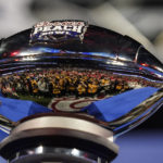 
              Photographers are reflected in the The George P. Crumbley Trophy after the Peach Bowl NCAA college football semifinal playoff game between Georgia and Ohio State, Sunday, Jan. 1, 2023, in Atlanta. Georgia won 42-41. (AP Photo/Brynn Anderson)
            