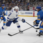 
              Tampa Bay Lightning's Brayden Point (21) shoots as St. Louis Blues' Justin Faulk (72) and Jordan Kyrou (25) defend during the third period of an NHL hockey game Saturday, Jan. 14, 2023, in St. Louis. (AP Photo/Jeff Roberson)
            