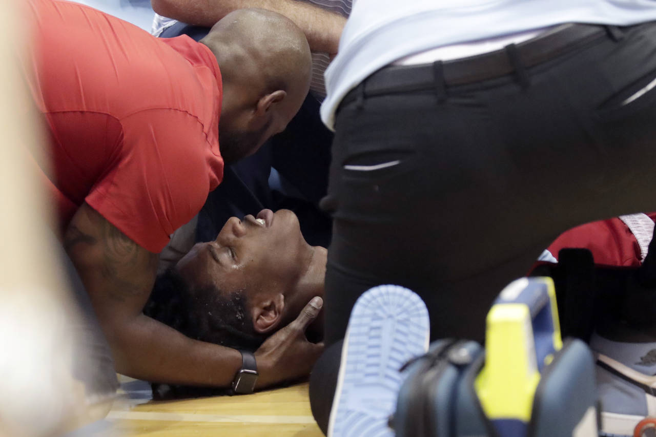 North Carolina State player Terquavion Smith, bottom, is tended by medical personnel after he crash...