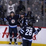 
              Winnipeg Jets' Axel Jonsson-Fjallby (71) celebrates his goal against the Vancouver Canucks with Sam Gagner (89) and Kevin Stenlund (28) during the second period of an NHL hockey game in Winnipeg, Manitoba, Sunday, Jan. 8, 2023. (Fred Greenslade/The Canadian Press via AP)
            