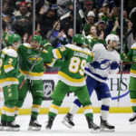 
              Minnesota Wild defenseman Calen Addison (2) is congratulated by Ryan Hartman (38), Frederick Gaudreau (89) and Matt Boldy (12) after scoring a goal, while Tampa Bay Lightning left wing Brandon Hagel (38) skates through during the second period during an NHL hockey game Wednesday, Jan. 4, 2023, in St. Paul, Minn. (AP Photo/Andy Clayton-King)
            