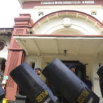 
              Police carry riot shields in front of a court building in Surabaya, East Java, Indonesia, Monday, Jan, 16, 2023. The court began trial Monday against five men on charges of negligence leading to deaths of 135 people after police fired tear gas inside a soccer stadium, setting off a panicked run for the exits in which many were crushed. (AP Photo/Trisnadi)
            
