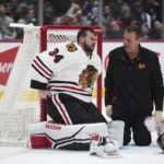 
              Chicago Blackhawks goalie Petr Mrazek reacts as he receives attention from head athletic trainer Mike Gapski after teammate Max Domi checked Vancouver Canucks' Dakota Joshua on top of him during the third period of an NHL hockey game Tuesday, Jan. 24, 2023, in Vancouver, British Columbia. (Darryl Dyck/The Canadian Press via AP)
            