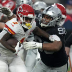 
              Kansas City Chiefs running back Jerick McKinnon (1) runs with the ball past Las Vegas Raiders defensive tackle Jerry Tillery (90) during the second half of an NFL football game Saturday, Jan. 7, 2023, in Las Vegas. (AP Photo/John Locher)
            
