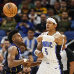 
              Orlando Magic forward Paolo Banchero (5) passes the ball while defended by Indiana Pacers forward Aaron Nesmith (23) during the first half of an NBA basketball game Wednesday, Jan. 25, 2023, in Orlando, Fla. (AP Photo/Kevin Kolczynski)
            