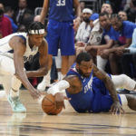 
              Dallas Mavericks guard Frank Ntilikina, left, dives for a loose ball along with Los Angeles Clippers guard John Wall during the first half of an NBA basketball game Tuesday, Jan. 10, 2023, in Los Angeles. (AP Photo/Mark J. Terrill)
            
