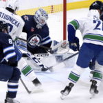 
              Winnipeg Jets goaltender David Rittich (33) makes a save against Vancouver Canucks' Jack Studnicka (18) and Curtis Lazar (20) during second-period NHL hockey game action in Winnipeg, Manitoba, Sunday, Jan. 8, 2023. (Fred Greenslade/The Canadian Press via AP)
            
