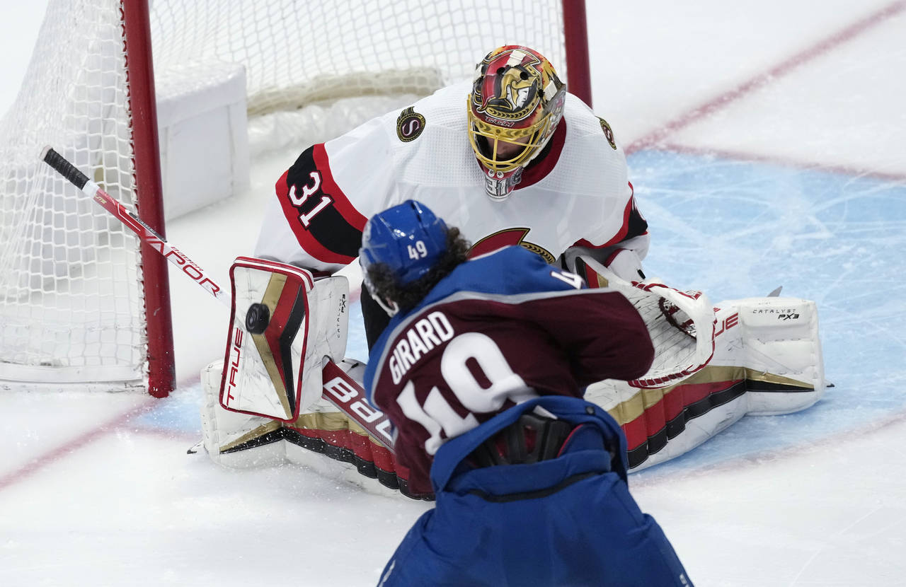 Ottawa Senators goaltender Anton Forsberg, top, makes a save of a shot off the stick of Colorado Av...