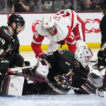 
              Arizona Coyotes goaltender Connor Ingram, middle, makes a save on shot by Detroit Red Wings center Andrew Copp (18) as Coyotes defensemen Shayne Gostisbehere (14) and Jakob Chychrun (6) help out during the second period of an NHL hockey game in Tempe, Ariz., Tuesday, Jan. 17, 2023. (AP Photo/Ross D. Franklin)
            