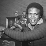 
              FILE - Southern California tailback Charles White puts his arms around the Heisman Trophy won by O.J. Simpson in 1968 after White was announced as the winner of the 1979 Heisman Trophy, Dec. 3, 1979, in Los Angeles. White died Wednesday, Jan. 11, 2023. He was 64. USC announced the death of White, who is still the Trojans' career rushing leader with 6,245 yards. The nine-year NFL veteran died of cancer, the school said. (AP Photo/Wally Fong, File)
            