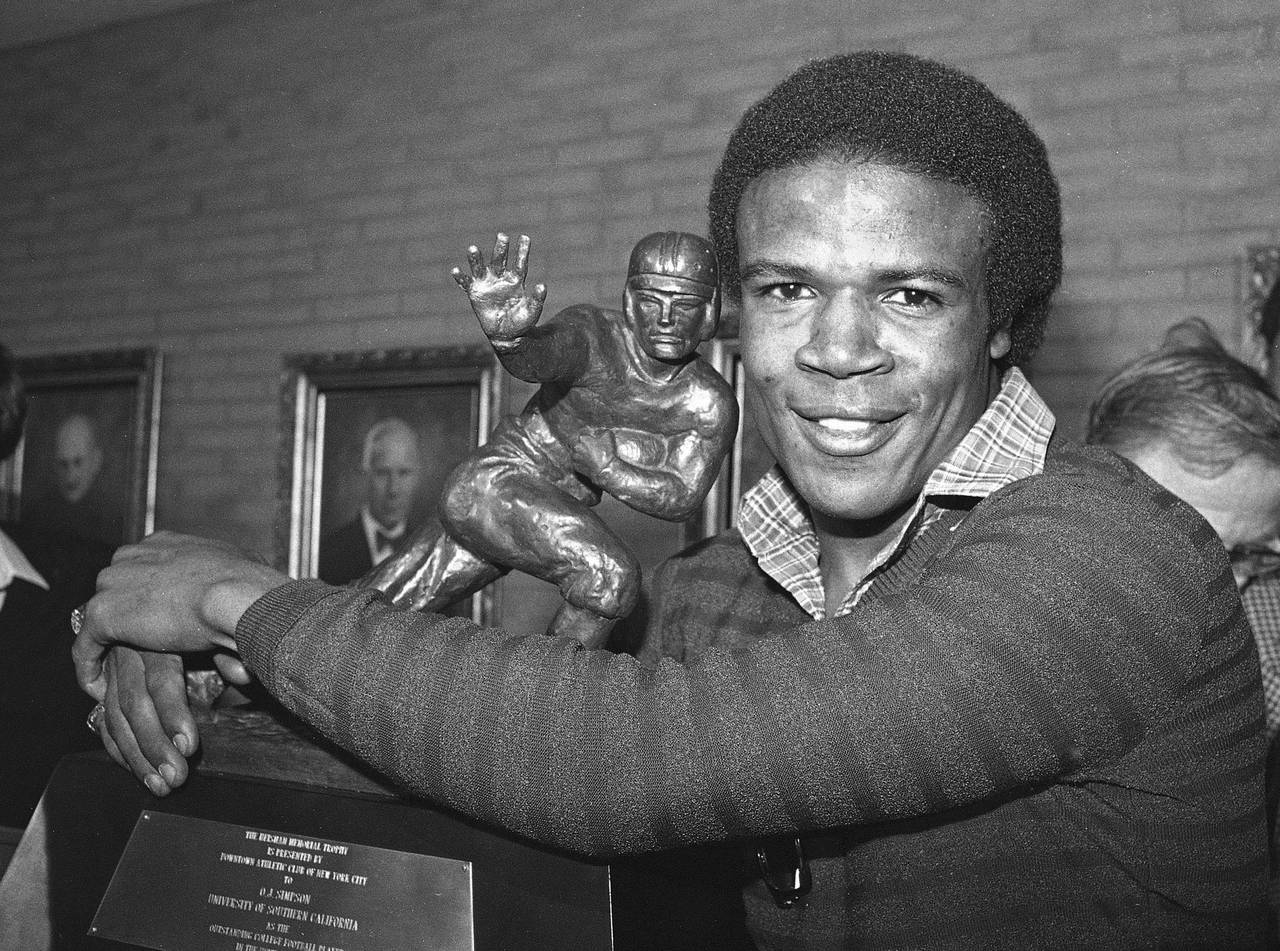 FILE - Southern California tailback Charles White puts his arms around the Heisman Trophy won by O....
