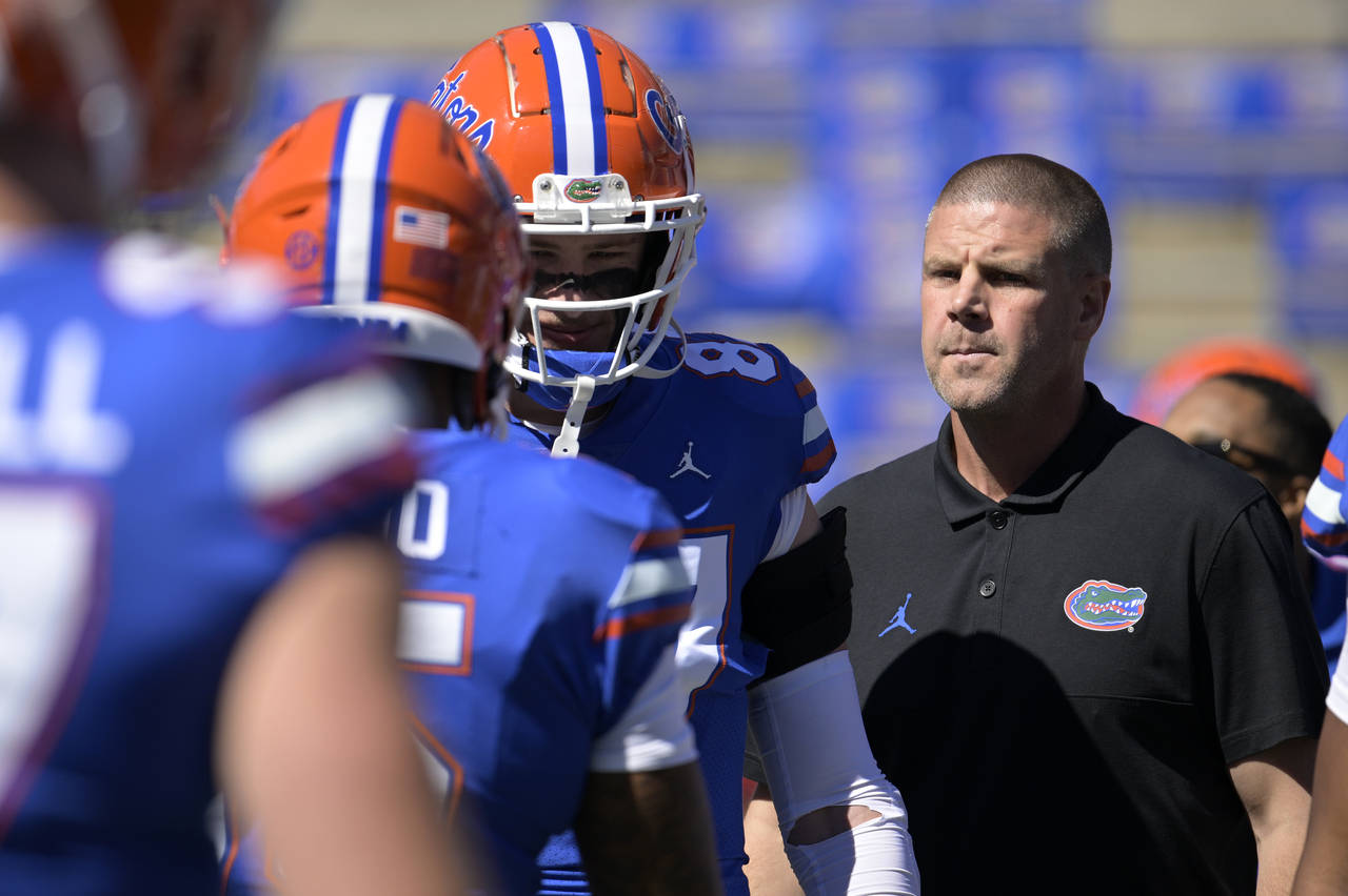FILE - Florida head coach Billy Napier, right, watches players warm up before an NCAA college footb...