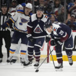 
              Colorado Avalanche center Nathan MacKinnon, front, struggles to skate off the ice after being injured in a scrum for the puck in front of the net as right wing Logan O'Connor, center, and St. Louis Blues center Brayden Schenn look on in the third period of an NHL hockey game Saturday, Jan. 28, 2023, in Denver. (AP Photo/David Zalubowski)
            