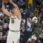 
              Denver Nuggets center Nikola Jokic (15) goes up for a basket after clearing Minnesota Timberwolves center Naz Reid out of the lane in the first half of an NBA basketball game Wednesday, Jan. 18, 2023, in Denver. (AP Photo/David Zalubowski)
            
