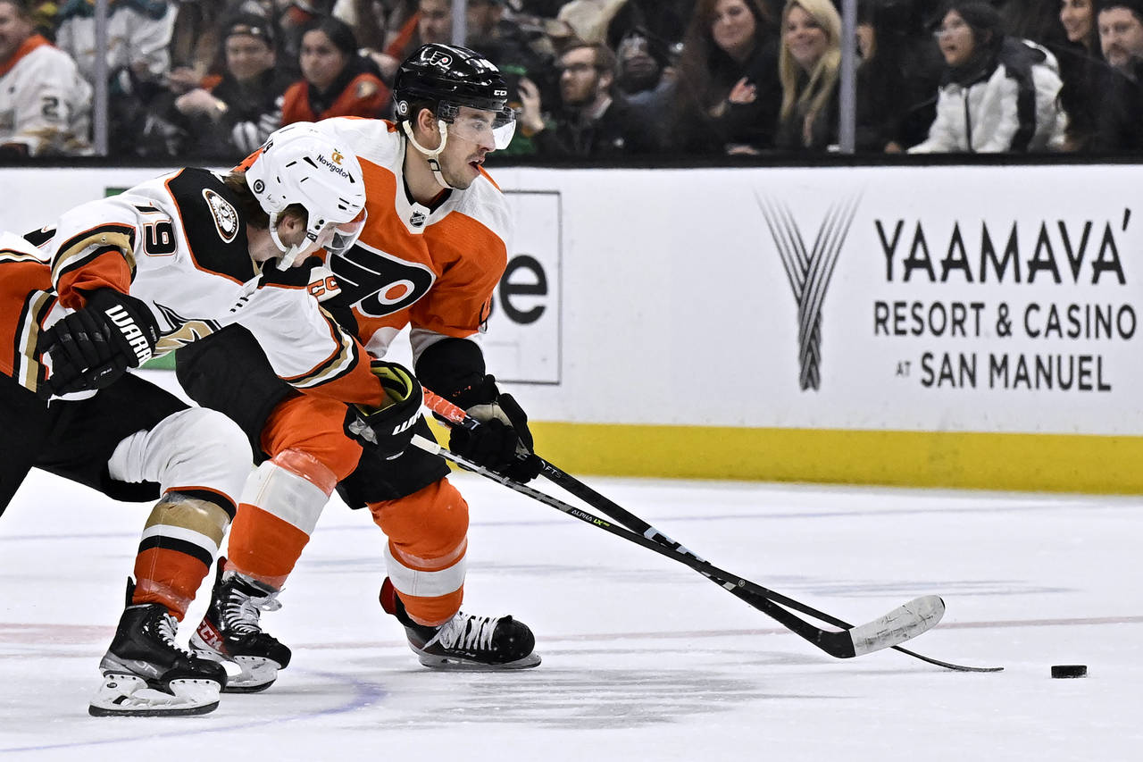 Philadelphia Flyers center Morgan Frost, right, controls the puck under pressure from Anaheim Ducks...