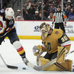
              Colorado Avalanche center Andrew Cogliano, left, redirects the puck at Vegas Golden Knights goaltender Logan Thompson in the third period of an NHL hockey game, Monday, Jan. 2, 2023, in Denver. (AP Photo/David Zalubowski)
            