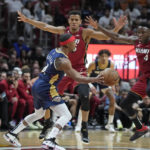 
              New Orleans Pelicans guard Devonte' Graham, foreground, passes past Miami Heat guard Victor Oladipo, right, and center Orlando Robinson (25) during the first half of an NBA basketball game, Sunday, Jan. 22, 2023, in Miami. (AP Photo/Wilfredo Lee)
            