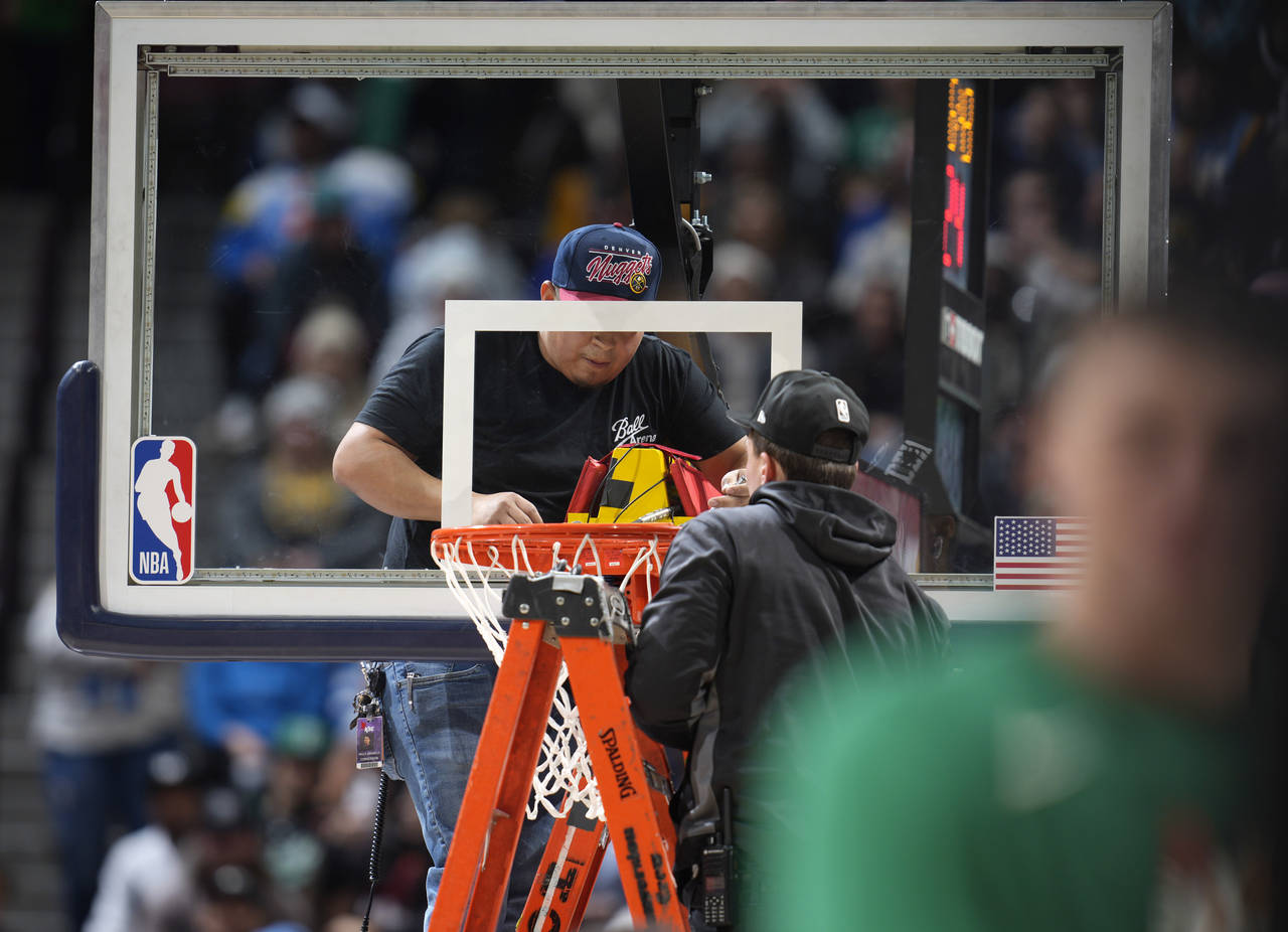 Workers struggle to replace the rim after it was bent during a dunk by Boston Celtics center Robert...