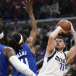 
              Dallas Mavericks guard Luka Doncic, right, shoots as Los Angeles Clippers guard Terance Mann, center, and forward Robert Covington defend during the first half of an NBA basketball game Tuesday, Jan. 10, 2023, in Los Angeles. (AP Photo/Mark J. Terrill)
            