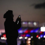
              A man uses a cell phone to capture images at Federal Hill Park with M&T Bank, the home stadium of the Baltimore Ravens, giving a backdrop in the colors of the Buffalo Bills in support of safety Damar Hamlin, Wednesday, Jan. 4, 2023, in Baltimore. Hamlin was taken to the hospital after collapsing on the field during an NFL football game against the Cincinnati Bengals on Monday night. (AP Photo/Julio Cortez)
            