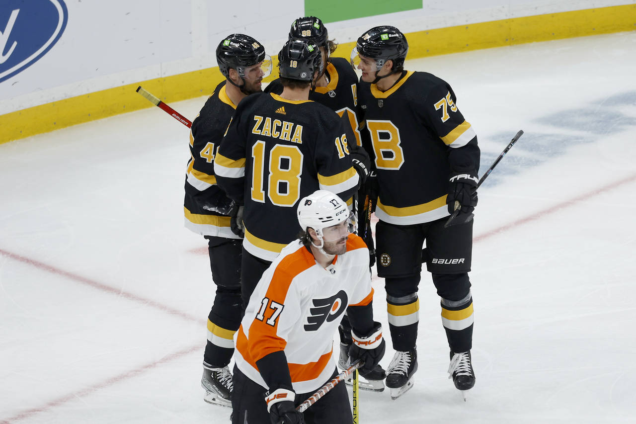 Philadelphia Flyers center Zack MacEwen skates away as Boston Bruins players congratulate Pavel Zac...