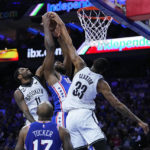 
              Philadelphia 76ers' Joel Embiid, center, leaps for a rebound against Brooklyn Nets' Kyrie Irving, left, and Nic Claxton during the first half of an NBA basketball game, Wednesday, Jan. 25, 2023, in Philadelphia. (AP Photo/Matt Slocum)
            