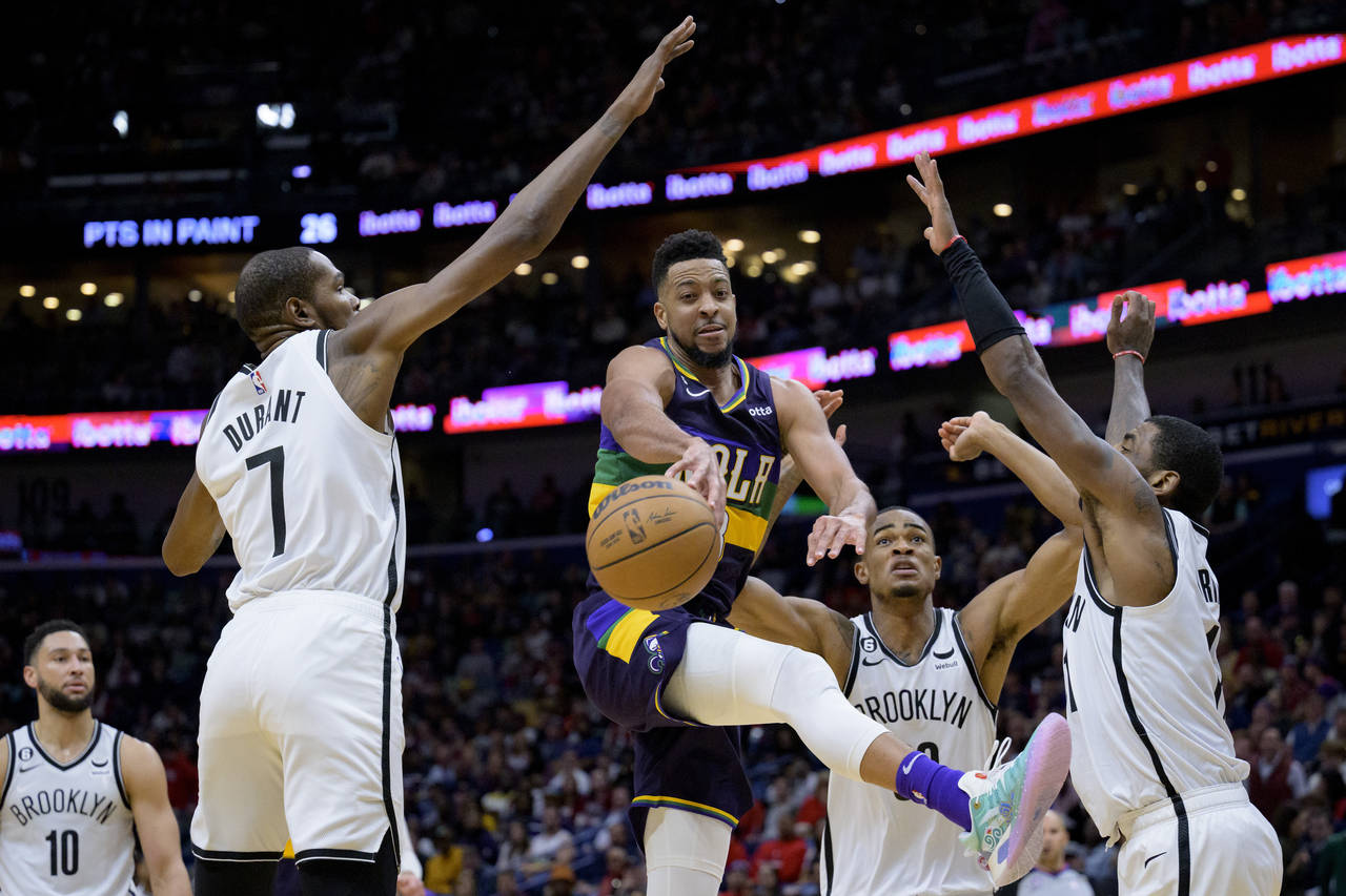New Orleans Pelicans guard CJ McCollum, center, is surrounded by the Brooklyn Nets forward Kevin Du...